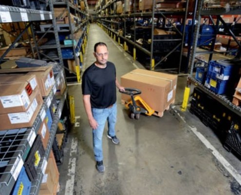 Man holding pallet jack from Miami Industrial Trucks in warehouse with box