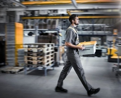 Man walking through warehouse with box in his hands - Miami Industrial Trucks